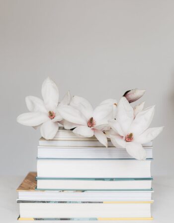 stack of books with magnolia flower on white table
